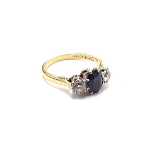 6299 - An 18ct gold three stone diamond and sapphire ring the central oval sapphire flanked by 0.20ct appro... 