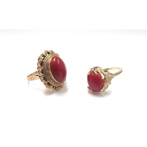 6155 - An oval cabochon coral ring in ornate wavy mount stamped18ct. Size N, 5.9g and another in ornate lea... 