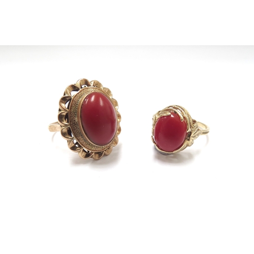 6155 - An oval cabochon coral ring in ornate wavy mount stamped18ct. Size N, 5.9g and another in ornate lea... 