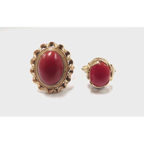 6155 - An oval cabochon coral ring in ornate wavy mount stamped18ct. Size N, 5.9g and another in ornate lea... 