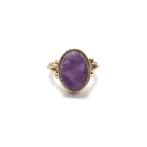 6121 - An unmarked gold ring with twisted design shank set with an oval flat cut amethyst. Size J, 4.6g