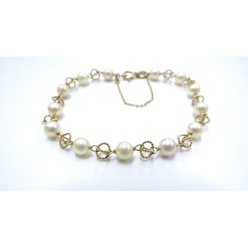 6276 - An 18ct gold bracelet with fancy link spaced by pearls, 20cm long, 7.5g