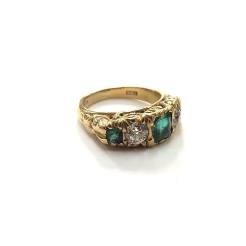 6281 - An 18ct gold ring with carved scroll shaped head, set with three graduated step cut emeralds (one ch... 