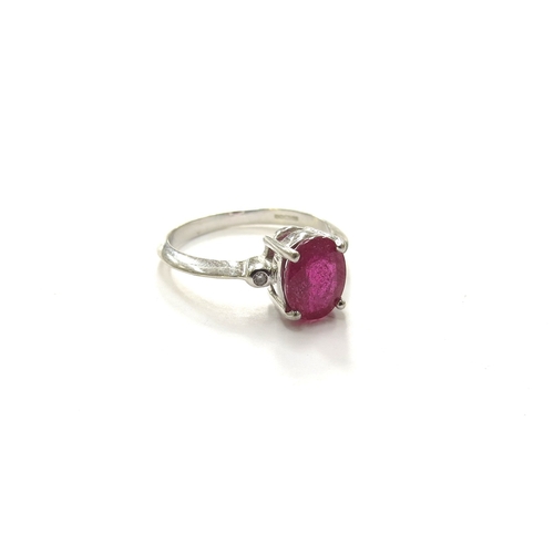 6096 - An 18ct white gold ring set with and oval ruby flanked by collet set diamonds. Size N, 3.4g