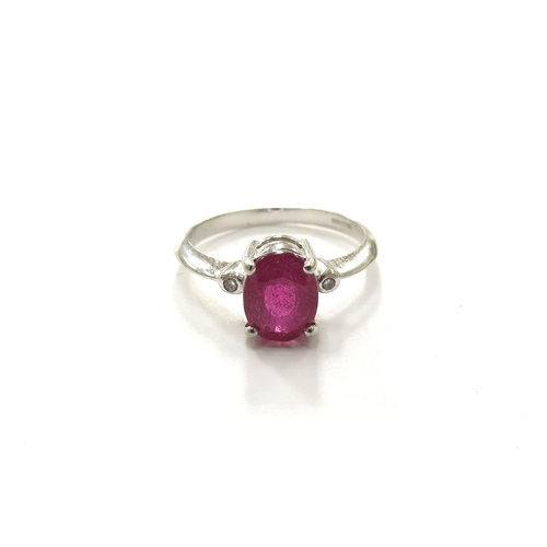 6096 - An 18ct white gold ring set with and oval ruby flanked by collet set diamonds. Size N, 3.4g