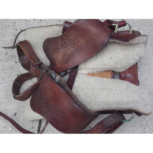 1049 - A tan leather Western saddle with leather stirrups, tooled botanical decoration and sheep’s wool lin... 