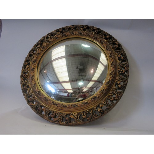 1041 - A mid-20th Century convex circular wall mirror in a moulded and gilded pierced foliate frame. 51.5 t... 