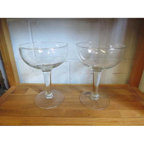 1128 - A pair of oversized champagne saucers, 26cm tall