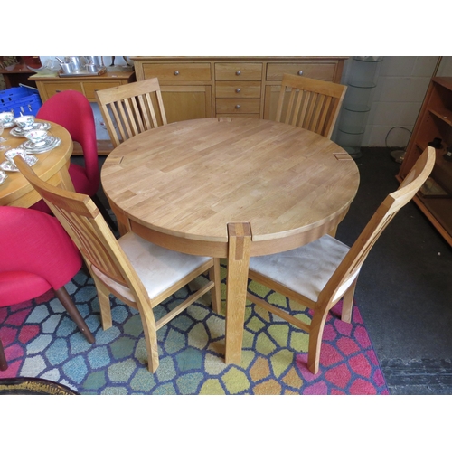 1131 - A natural oak extending circular dining table with internal folding leaf together with four chairs