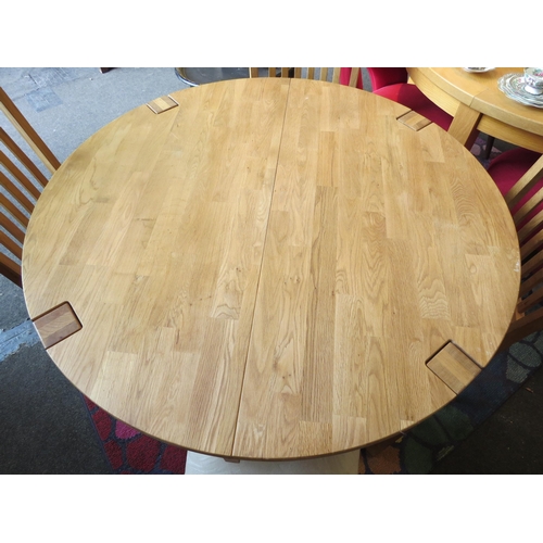 1131 - A natural oak extending circular dining table with internal folding leaf together with four chairs