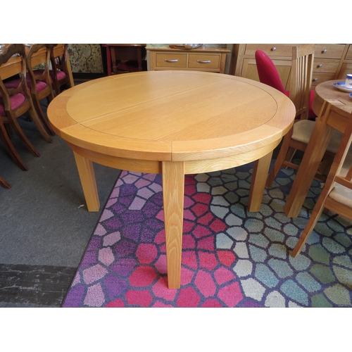 1134 - A natural oak extending circular dining table with internal fold-out leaf