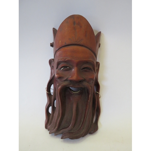 1324 - A Chinese carved wooden wall face mask as a bearded man, 31cm high