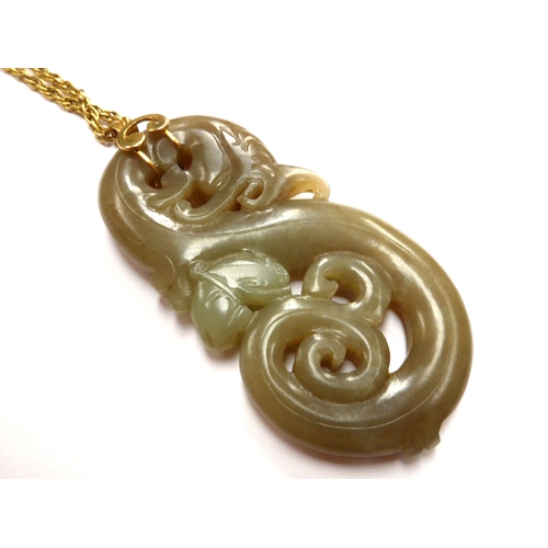 6338 - A carved Jade pendant of a dragon with bat like creature, 8cm x 4cm, hung on a gold chain stamped 18... 