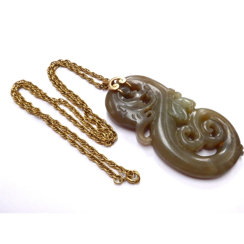 6338 - A carved Jade pendant of a dragon with bat like creature, 8cm x 4cm, hung on a gold chain stamped 18... 