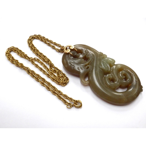 6338 - A carved Jade pendant of a dragon with bat like creature, 8cm x 4cm, hung on a gold chain stamped 18... 