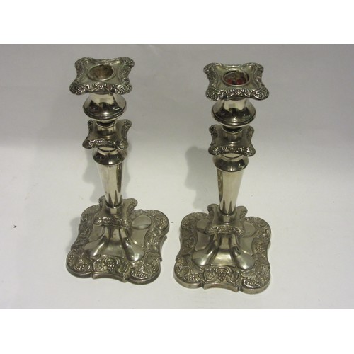 1029 - A pair of silver-plated candlesticks with floral embossed detail. 25cm tall.