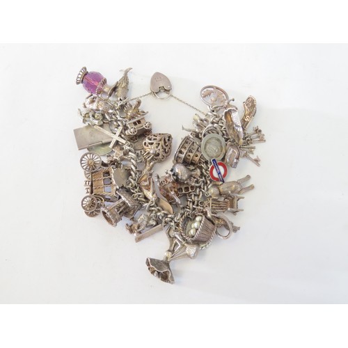 1055 - A silver charm bracelet with various charms including stagecoach, flamenco dancer, passport, koala e... 