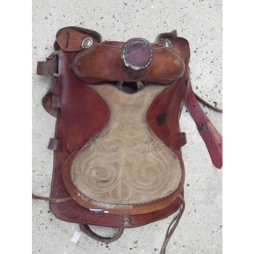 1049 - A tan leather Western saddle with leather stirrups, tooled botanical decoration and sheep’s wool lin... 