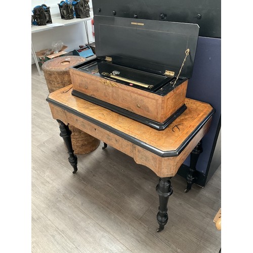 9010 - A cylinder musical box and table, figured walnut with crossbanding, ebonised turned supports to cast... 