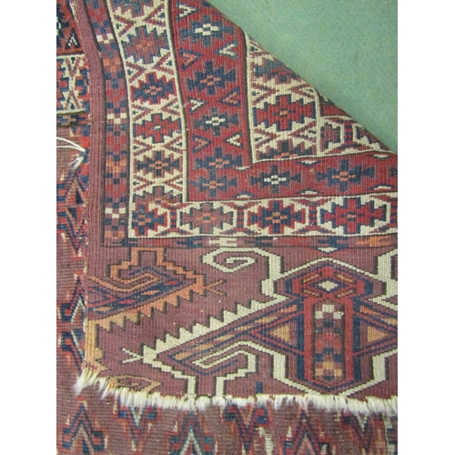 4117 - An Eastern red ground rug with geometric design, a/f, 180cm x 145cm