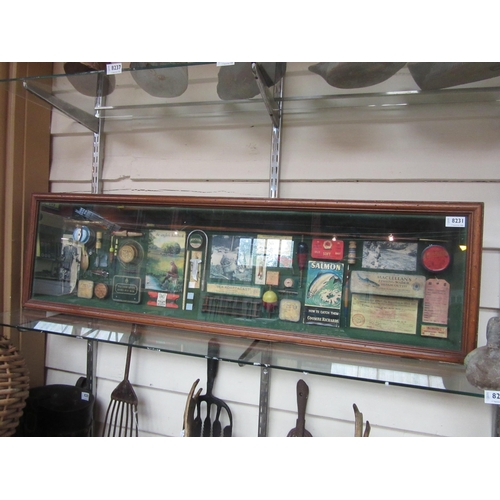 8231 - A glazed display cabinet containing fishing related items; split cane rod, books, lures etc