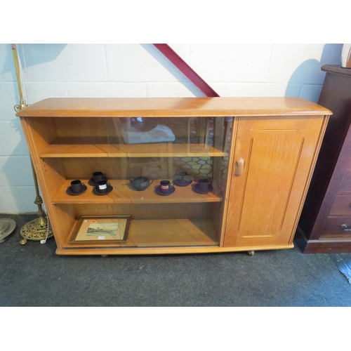 1011 - An Ercol style elm bookshelf with glass sliding doors and single door cupboard, 85cm tall x 134cm wi... 