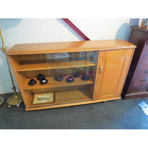 1011 - An Ercol style elm bookshelf with glass sliding doors and single door cupboard, 85cm tall x 134cm wi... 