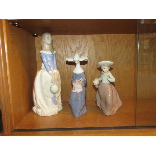 1013 - A Lladro figure of a seated Nun sewing, a Nao figure of a young girl holding bonnet and a similar Na... 