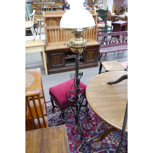 2256 - A wrought iron standard oil lamp with brass reservoir and white glass shade