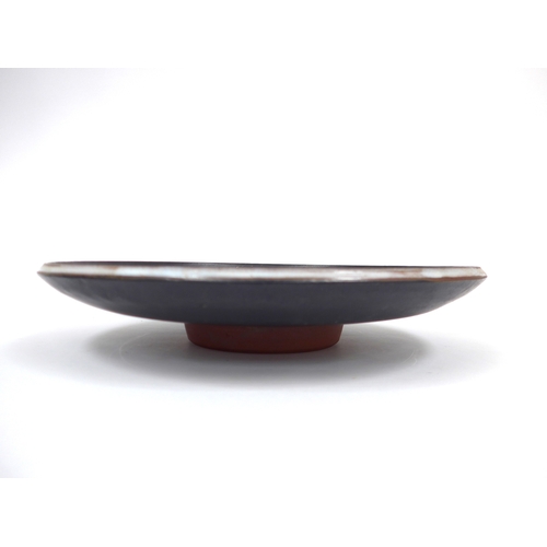 7022 - A mid 20th Century thrown pottery pedestal dish, black glazed with stylised coloured glaze design. I... 