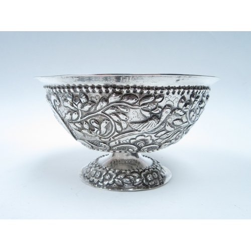 6415 - An Indian white metal pedestal bowl with repousse bird foliage and flower detail, 7cm tall, 13cm dia... 