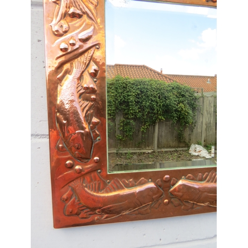 6002 - A Newlyn Arts & Crafts embossed copper mirror frame with fish and shell detail bevelled glass impres... 