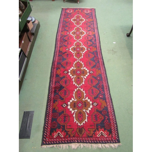 4239 - A red and blue ground Eastern wool runner rug with geometric design, tasselled ends, 288cm x 80cm