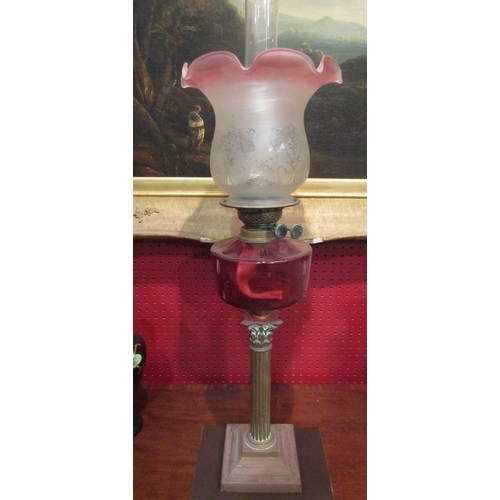 4062 - A Corinthian column oil lamp with cranberry glass reservoir