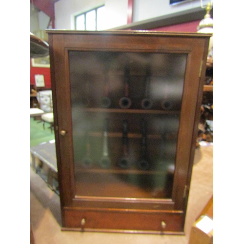 4266 - A mahogany pipe cabinet with ten pipes, mostly E.A. Carey.  Damage to beading, lower right edge