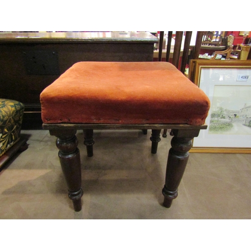 4286 - A 19th Century square low stool, the upholstered seat raised upon turned mahogany legs, 34cm tall