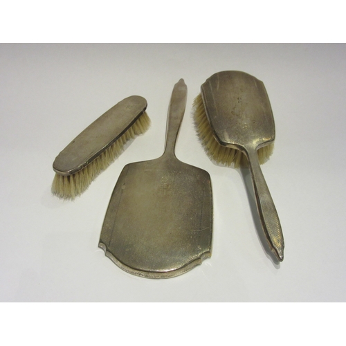 4387 - A silver dressing table set comprising of a hand mirror and two brushes, marked Birmingham 1939, Wil... 