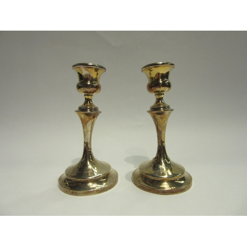 4400 - A pair of Chester silver candlesticks with weighted bases, 15cm tall, misshaped