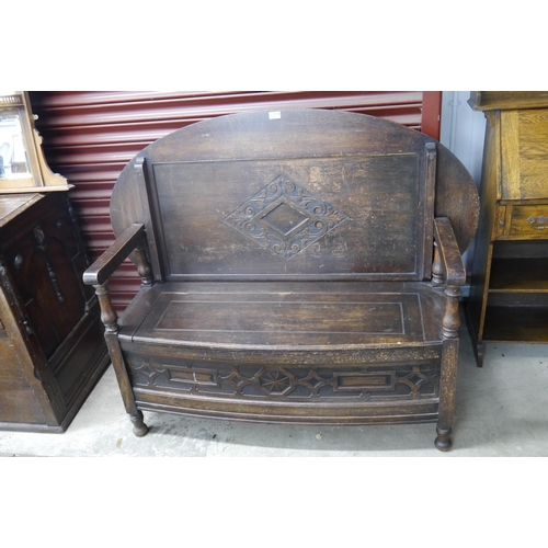 2125 - A 1920's oak monks bench table with fold over oval top and box seat