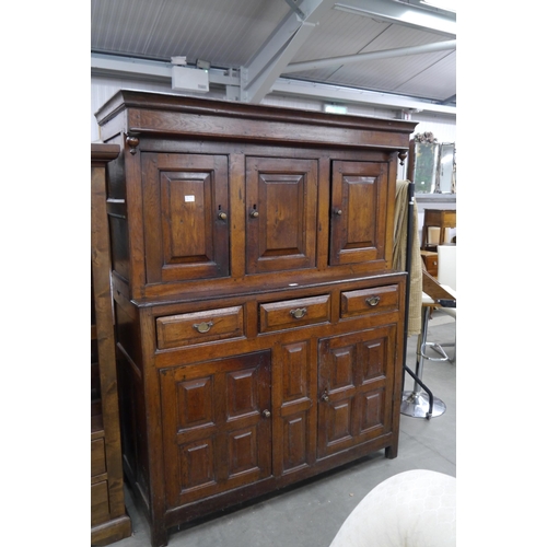 2399 - An 18th Century panelled oak court cupboard with three doors over three central drawers and two base... 