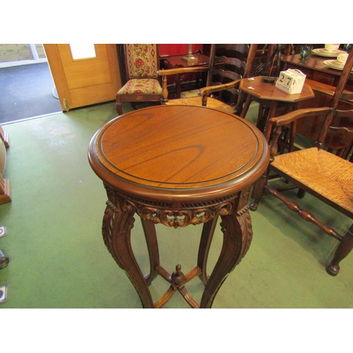 4055 - A reproduction hardwood jardiniere stand, circular top with carved and pierced frieze, shaped taperi... 