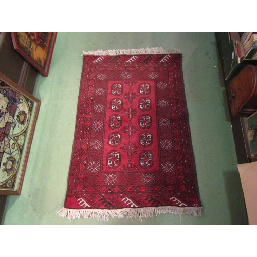 4244 - A small Eastern red ground wool rug, three central rows of guls, 110cm x 76cm