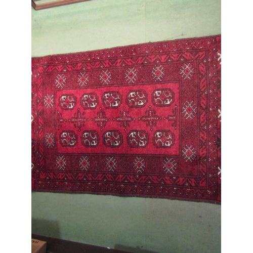 4244 - A small Eastern red ground wool rug, three central rows of guls, 110cm x 76cm