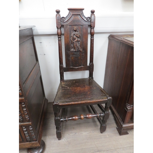 6033 - An early 18th Century oak high back chair with scrolled cresting rail over a figural carved panel de... 