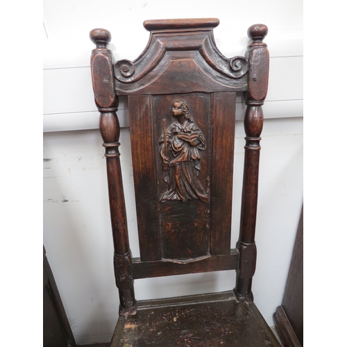 6033 - An early 18th Century oak high back chair with scrolled cresting rail over a figural carved panel de... 