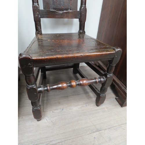 6033 - An early 18th Century oak high back chair with scrolled cresting rail over a figural carved panel de... 