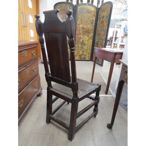 6033 - An early 18th Century oak high back chair with scrolled cresting rail over a figural carved panel de... 