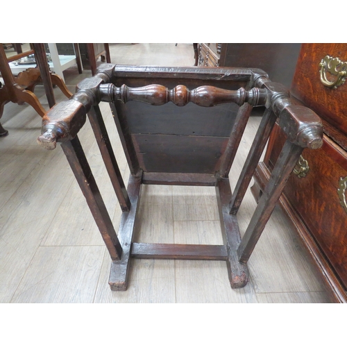 6033 - An early 18th Century oak high back chair with scrolled cresting rail over a figural carved panel de... 