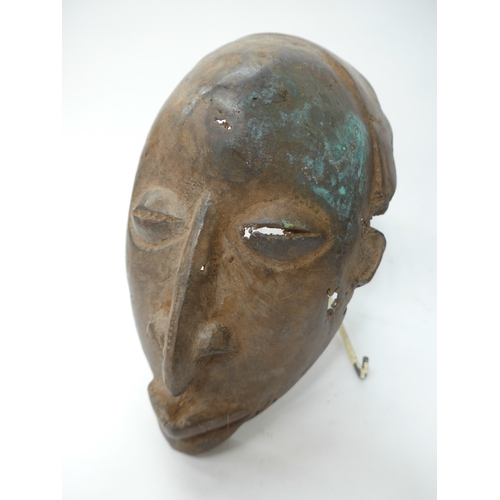 6298 - Three African cast masks including supernatural being. 27cm and 23cm tall