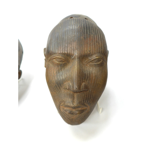 6299 - Three Benin bronze masks of human face form, holes to casting. 18.5cm, 19.5cm and 20.5cm tall